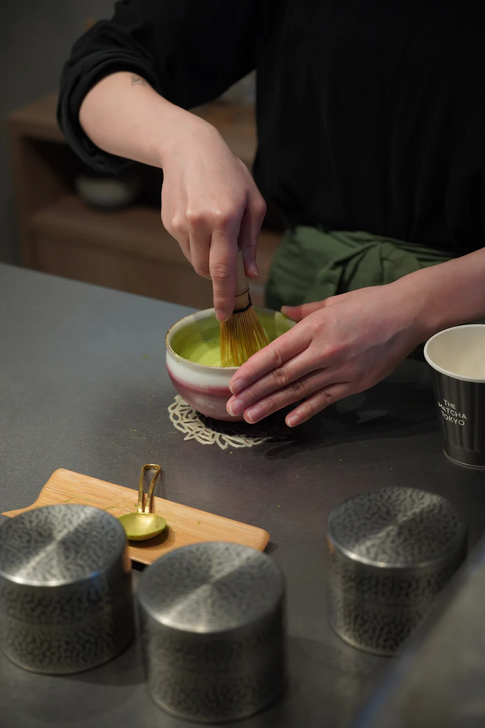 Persona batiendo té matcha con un batidor de bambú